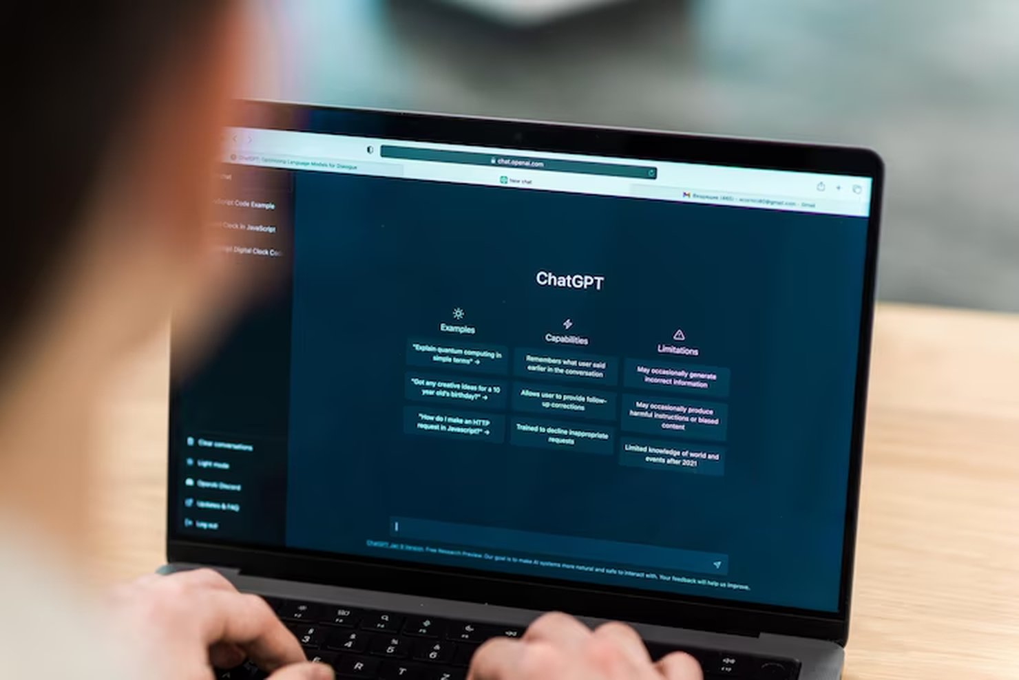 A person uses a laptop displaying the ChatGPT interface, highlighting example prompts, capabilities, and limitations — a practical setting for learning how to use ChatGPT effectively in real-world scenarios.